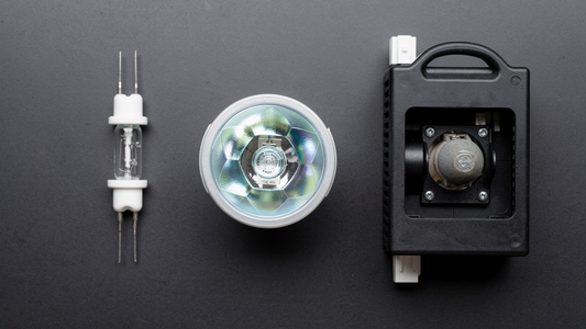 Projector lamp module beside a lit projector casting a bright image on a screen