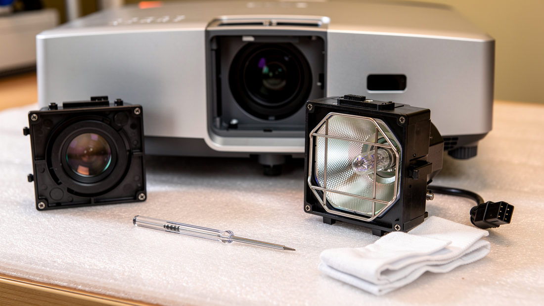 Projector opened on a bench with its lamp module and lens removed alongside tools