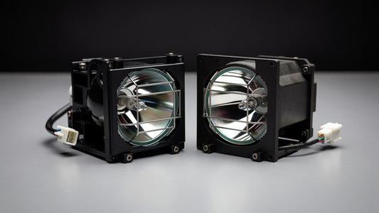 Two projector lamp modules side by side on a workbench for comparison